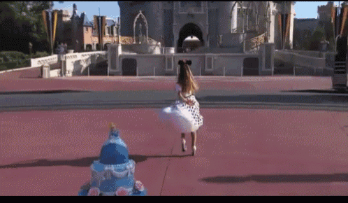 a girl in a polka dot dress is running in front of the castle