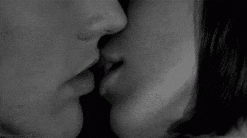 a black and white photo of a man and woman kissing