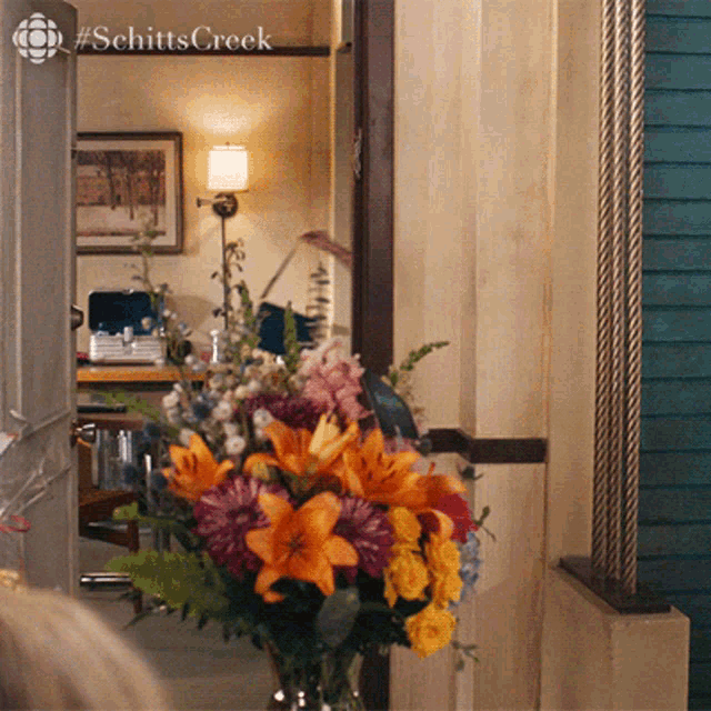 a bouquet of flowers sits in front of a sign that says schittscreek