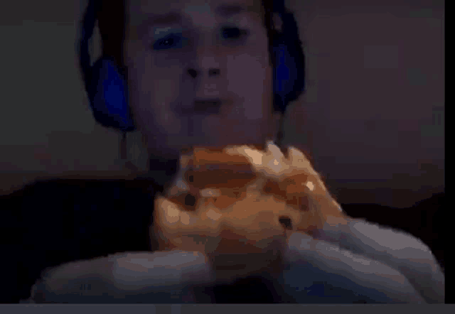 a man wearing blue headphones is eating a hamburger .