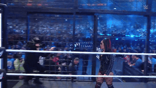 a woman is standing in a wrestling ring with a w logo on the side