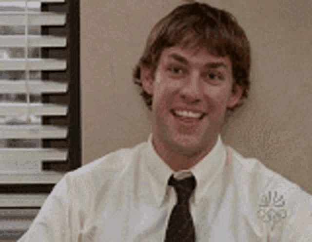 a man wearing a white shirt and tie is smiling