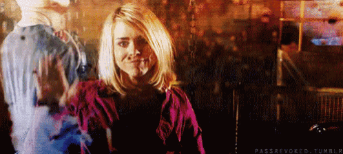 a woman in a pink shirt is smiling in a dark room