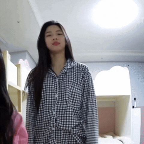 a woman in a plaid shirt is standing in a bedroom