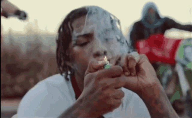 a man is smoking a cigarette with a bandana around his face .