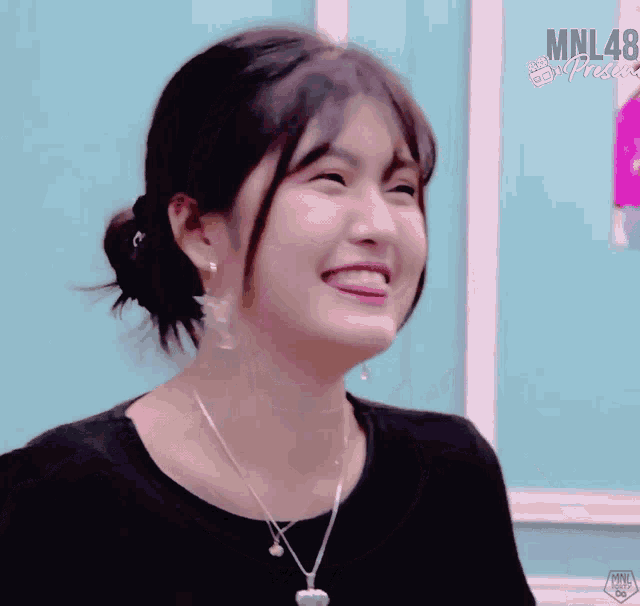 a girl is smiling in front of a wall that says mnl48 on it