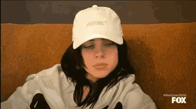 a woman is sitting on a couch wearing a white hat and a white hoodie .