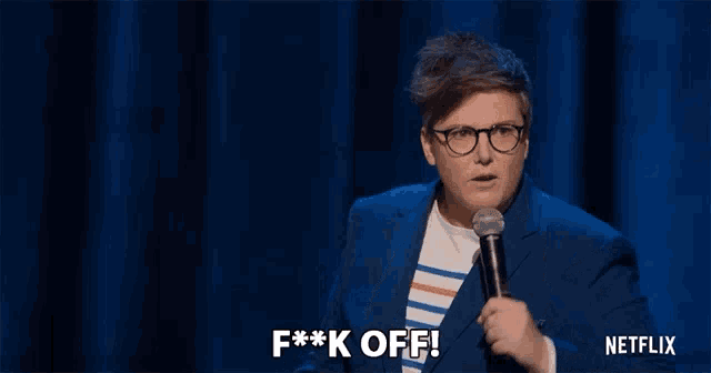 a woman with glasses is holding a microphone and saying f * ck off .