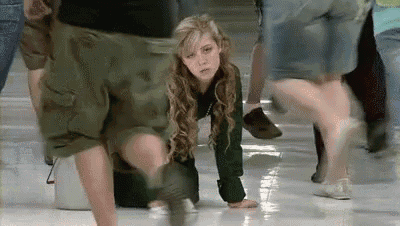 a woman is crawling on the floor in a crowd of people .