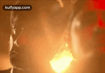 a man with a beard is smoking a cigarette in a dark room .
