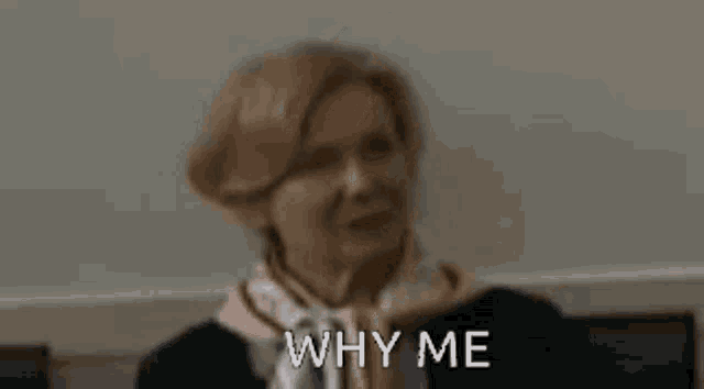 a woman with a scarf around her neck is sitting on a couch and says `` why me '' .