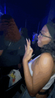a woman wearing glasses and a headband is dancing in a dark room
