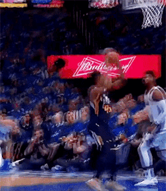 a basketball game is underway with a budweiser ad in the background
