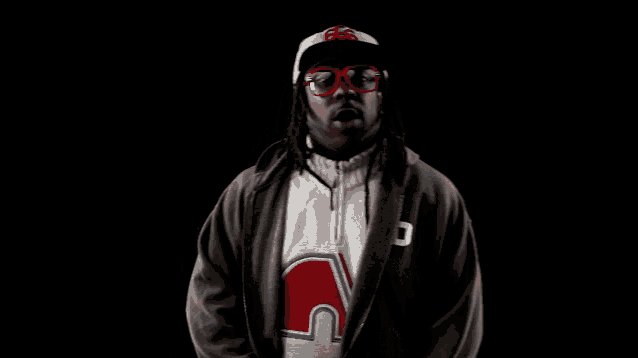 a man wearing glasses and a hat has the letter g on his hat