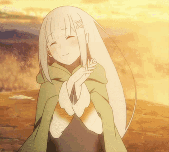 a girl with long white hair wearing a green cape is smiling