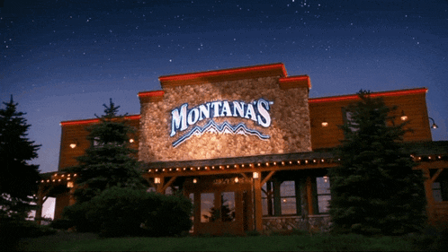 montana 's restaurant is lit up at night with trees in front of it