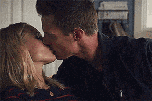 a man and a woman are kissing each other in a kitchen .