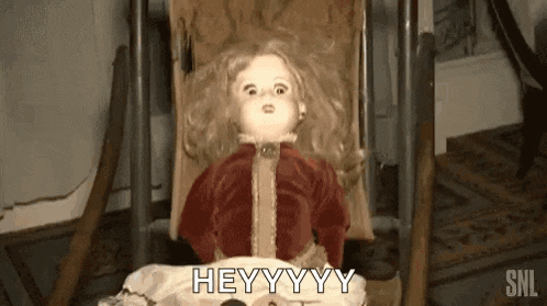 a doll is laying in a stroller in a room and says hey .