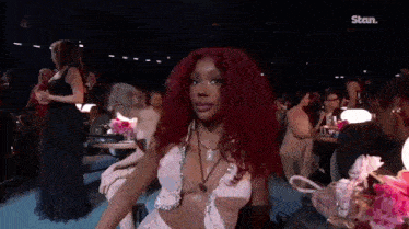 a woman with red hair is sitting in a chair in a crowded room .
