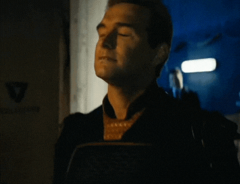 a man in a superhero costume is standing in a dark room looking at something .