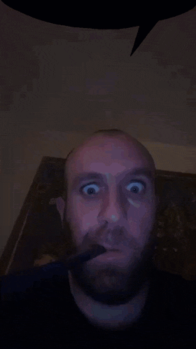 a man with a beard is smoking a cigarette and making a funny face