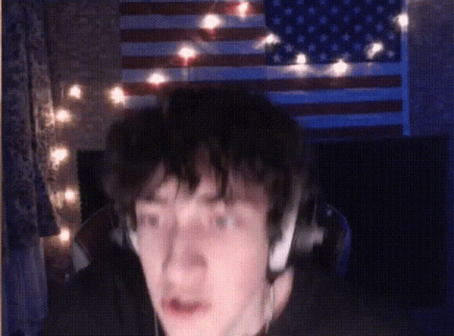 a man wearing headphones stands in front of a flag