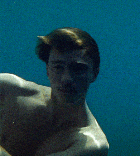 a man without a shirt is swimming in the ocean
