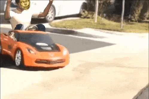 a man in a white shirt is driving a toy car on the street