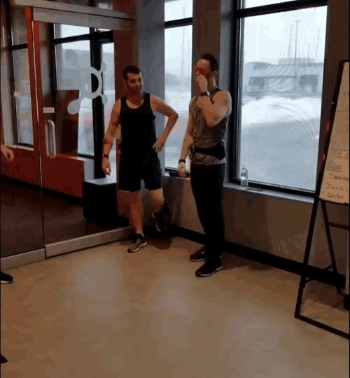 two men are standing in front of a white board that says " dumbbells "