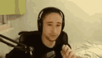 a man wearing headphones is sitting in front of a microphone on a bed .