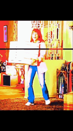 a woman with red hair is carrying a box in a room .
