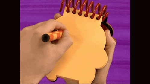 a person is writing on a yellow notepad with a red marker