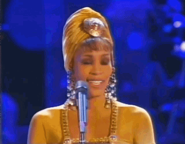 a woman in a turban singing into a microphone