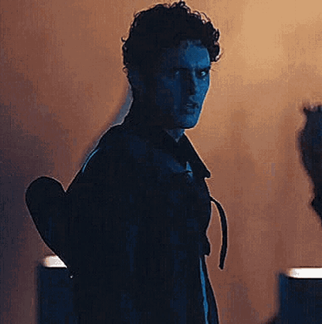 a man is standing in a dark room holding a heart in his hand .