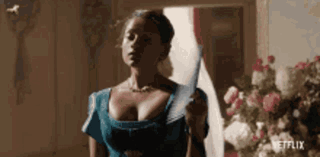 a woman in a blue dress is standing in a room holding a feather .