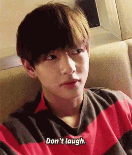 a young man in a red and black striped shirt is sitting on a couch and says do n't laugh .