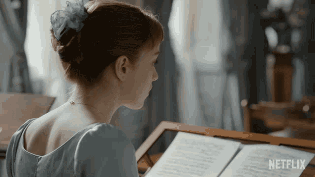 a woman sitting at a piano with a netflix logo on the bottom of the screen