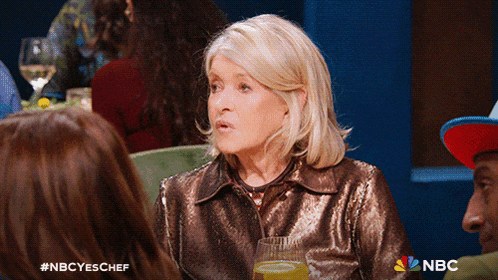 a woman in a sequined jacket is sitting at a table with other people and a nbc logo on the bottom