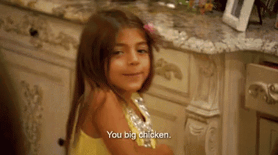 a little girl in a yellow dress is sitting in front of a counter .