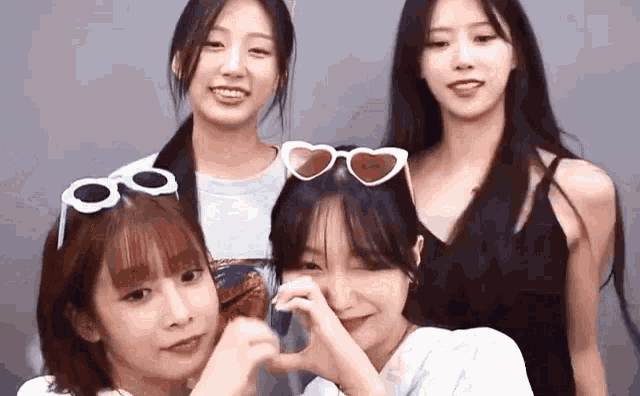 a group of young women are posing for a picture together while wearing heart shaped sunglasses .