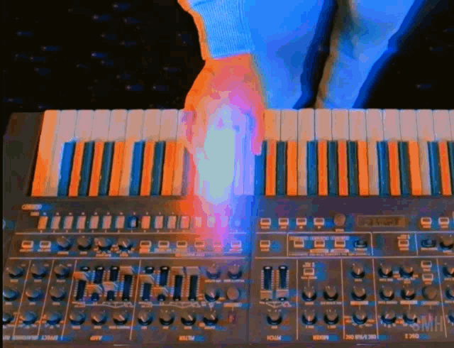 a person is playing a keyboard with a blue light coming out of the keyboard .