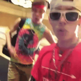 a man wearing sunglasses and a tie dye shirt poses for a picture