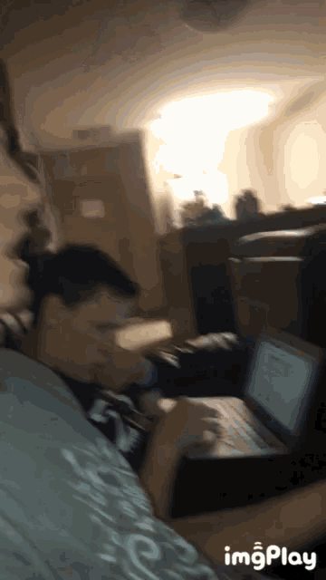a blurry picture of a person using a laptop with imgplay at the bottom right