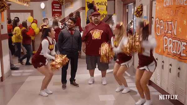 a group of cheerleaders are dancing in a hallway with a sign that says brown pride