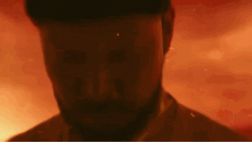 a close up of a man 's face with a beard in a dark room .