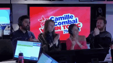 a group of people sitting in front of a camille combal sign