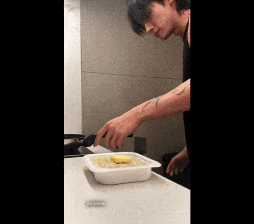 a man is preparing food in a plastic container with butter