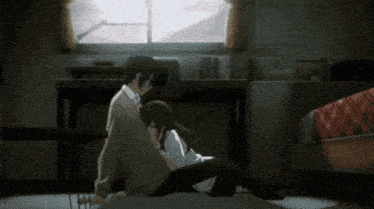a man and a woman are sitting on the floor in a dark room .