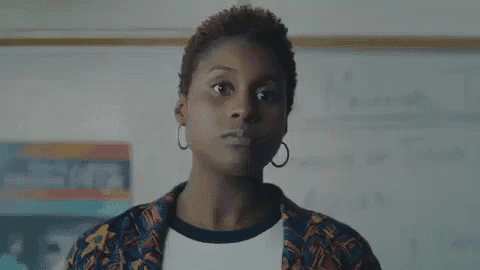 a woman is standing in front of a whiteboard in a classroom and looking at the camera .