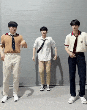 three young men are dancing in front of a wall with one wearing a shirt that says gucci
